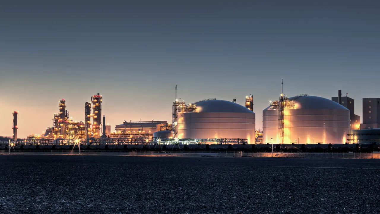 Twilight refinery with domed tanks for natural gas liquids under a gradient blue-orange sky.